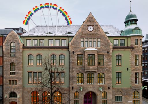 Fasade foto av bygg i jugendstil med et skilt på taket i regnbuefarger.