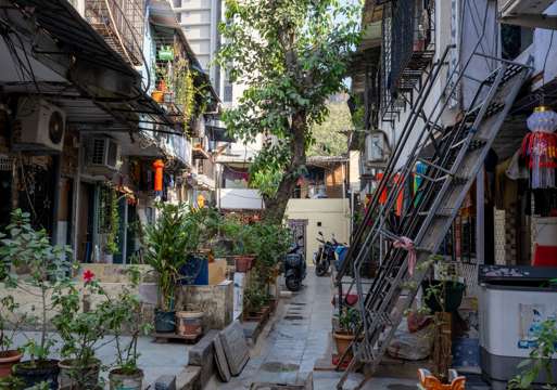 Foto av et fargerikt nabolag i Mumbai med mye planter og personlige gjenstander.