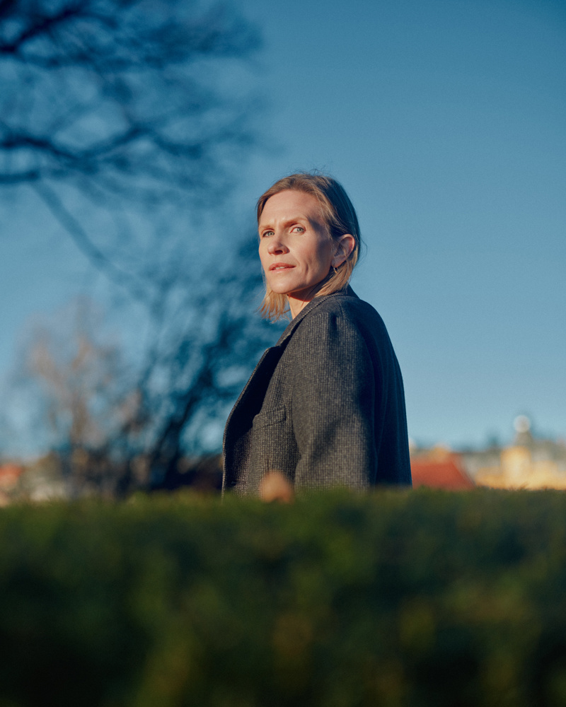 Portrett foto av Inger Therese Hoff, blå himmel bak og en hekk fremfor.