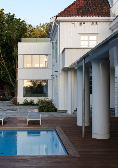 Foto av resort med hvitmalt bygg, store søyler, badebasseng og trær i bakgrunnen.