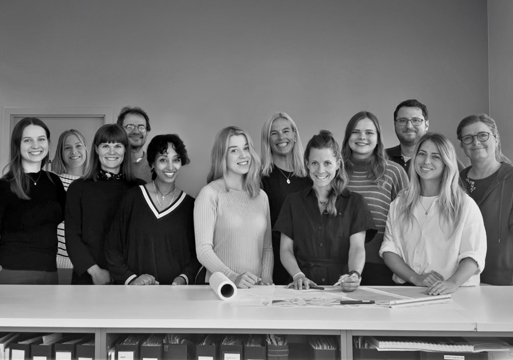 Gruppebilde av alle i Østengen & Bergo stående fremfor et langt hvitt bord.